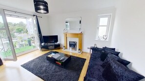 A modern living room with a fireplace, a television, and a sofa. - Orange Apartments - 150e Rusbislaw Mansions (Aberdeen)