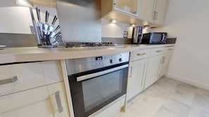 A modern kitchen with a gas stove, oven, microwave, and stainless steel utensils.
