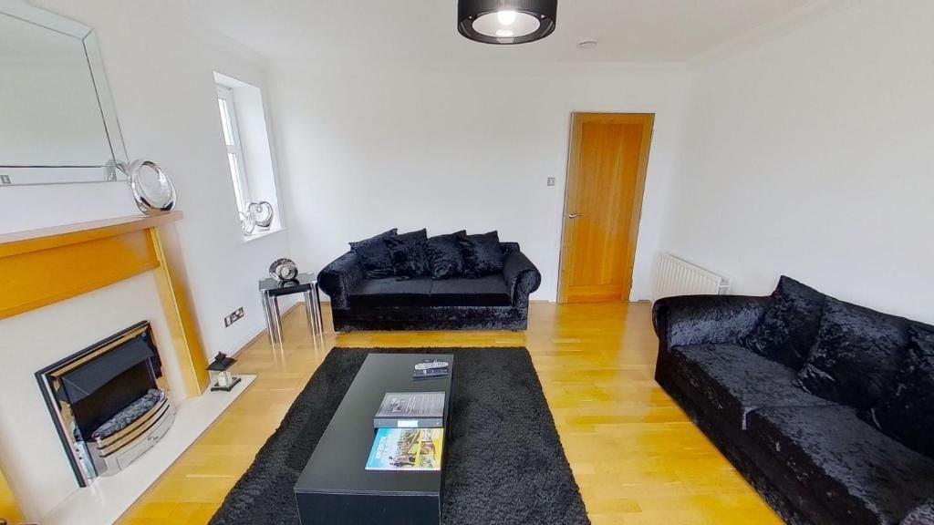 Un salon avec une cheminée, un canapé noir, une table basse et un miroir.