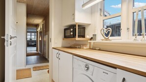 Una cucina moderna con mobili bianchi, un piano di lavoro in legno, un forno a microonde, un tostapane e una lavatrice.