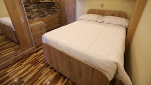 Un dormitorio pequeño con cama de madera, armario empotrado y pared con diseño de piedra.