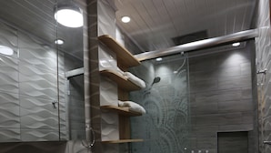 Un baño moderno con ducha de vidrio, inodoro blanco y tocador con lavamanos.