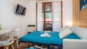 A bedroom with a bed, a desk, a chair, a TV, and a window with curtains. - GuestHost - Da Crispe Studio - 550 m far from the Golf Club (Tarvisio)