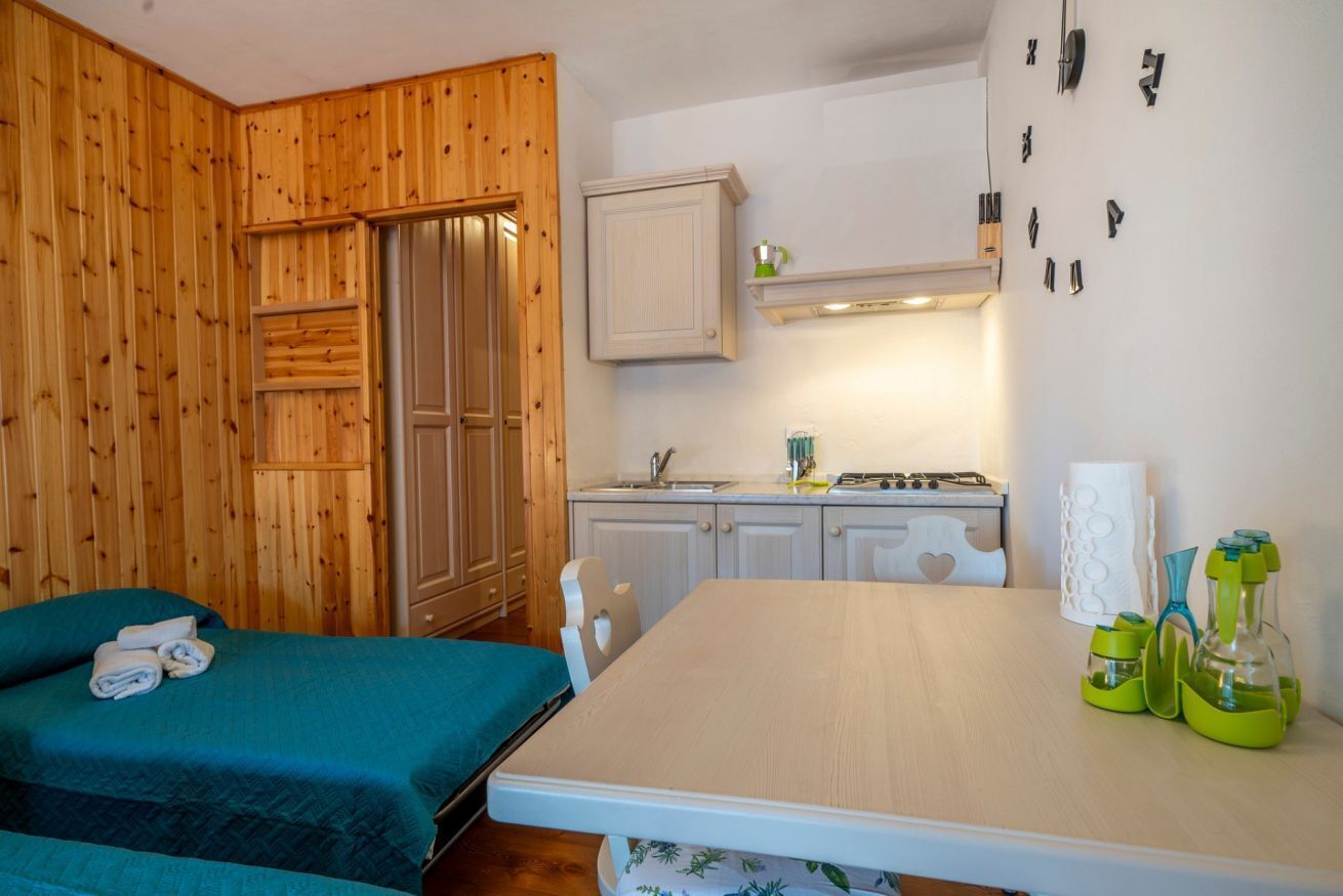 Ein Zimmer mit zwei Betten, einer Küchenzeile und einer Holzwand.