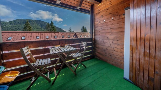 A wooden cabin with a balcony, green artificial grass, and a view of mountains. - GuestHost - Da Crispe Studio - 550 m far from the Golf Club (Tarvisio)