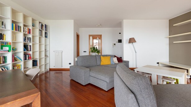 A living room with a sectional sofa, a wooden coffee table, a bookshelf, and a white desk with a lamp. - GuestHost - Milan-Rubattino Comfy APT - with 2 Terrace (Milano)