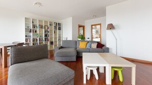 A modern living room with a grey sofa, a white table, and a bookshelf filled with books. - GuestHost - Milan-Rubattino Comfy APT - with 2 Terrace (Milano)