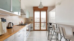 A modern kitchen with a wooden countertop, stainless steel appliances, and a view through a glass door to an outdoor balcony. - GuestHost - Milan-Rubattino Comfy APT - with 2 Terrace (Milano)