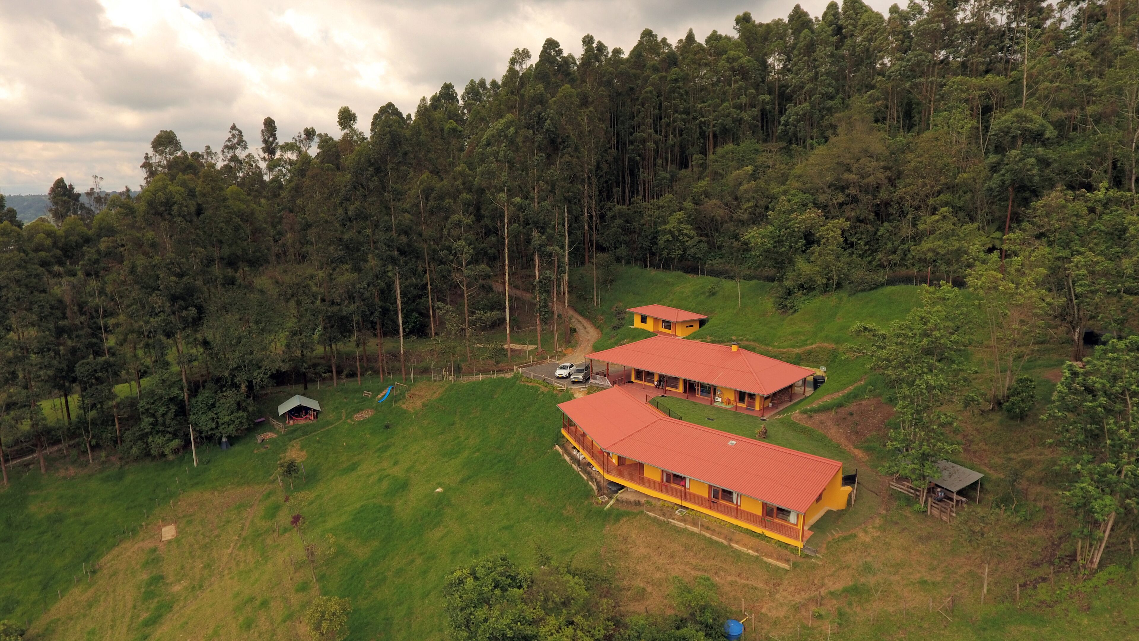 Una propiedad rural con dos edificios principales, una cabaña pequeña y una casa grande con techo rojo.
