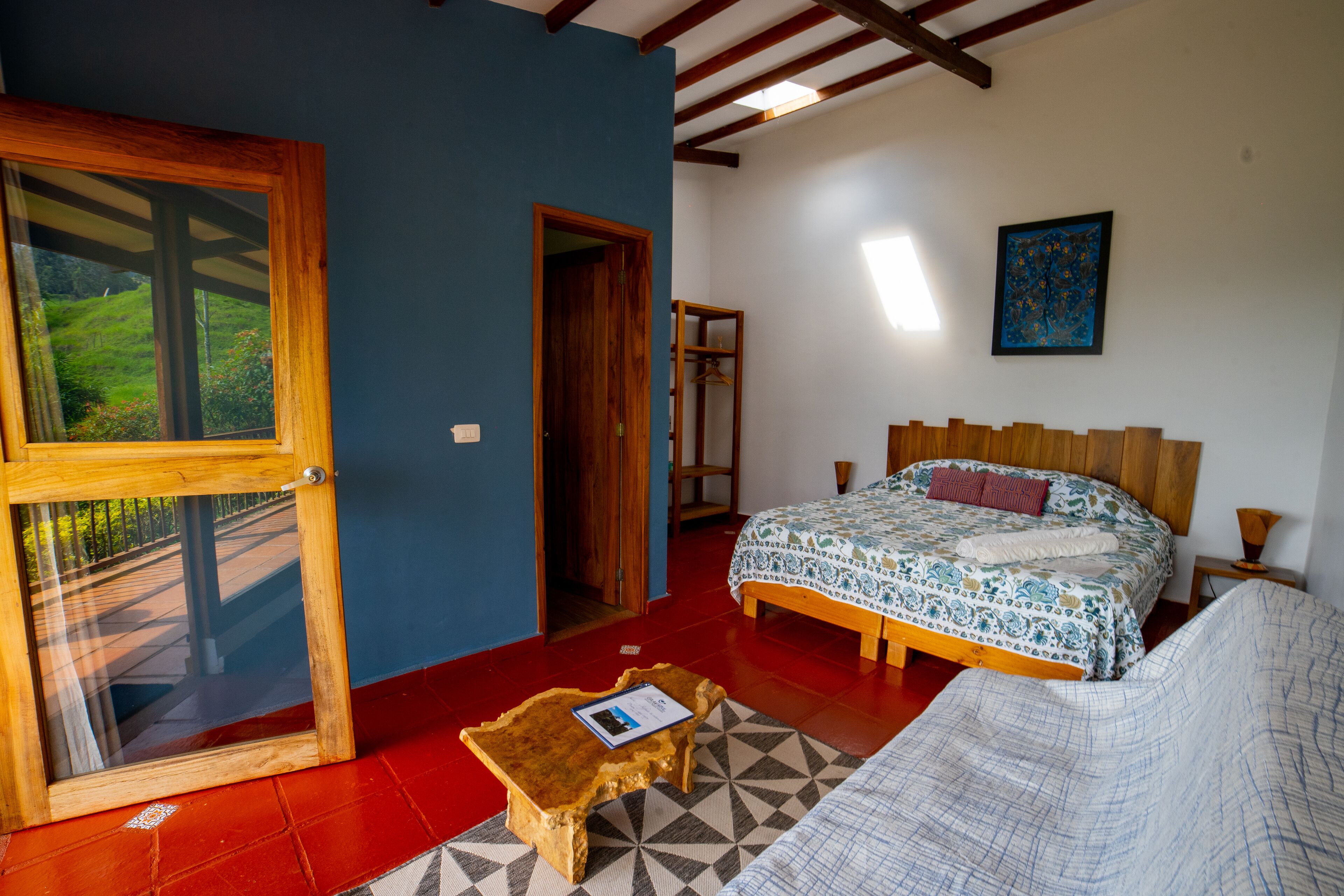 Un dormitorio con cama, cabecera de madera, ventana y puerta que da a un balcón.