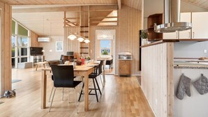 Eine geräumige Küche mit Holzschränken, einem großen Herd und einem Essbereich mit einem Holztisch und Stühlen.