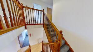 A wooden staircase with a handrail, leading to a landing with a door and a fire extinguisher on the wall. - Orange Apartments Bothwell Road (Aberdeen)