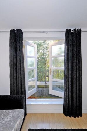 A room with a large window, a bed, and a black rug. - Orange Apartments Beechgrove (Aberdeen)