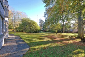 A well-maintained grassy area with a paved walkway, surrounded by trees and a building. - Orange Apartments Beechgrove (Aberdeen)