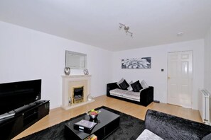 A living room with a flat-screen TV, a fireplace, a sofa, and a coffee table.