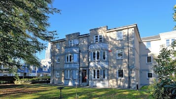 A multi-story residential building with a symmetrical facade, large windows, and a well-maintained lawn.