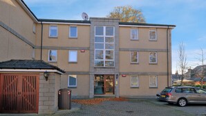 A multi-story residential building with a central entrance, a satellite dish, and a car parked in the driveway. - Orange Apartments Beechgrove (Aberdeen)