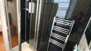 A room with a bed, a shower area with a glass door, and a towel rack. - Midway Guest House (Torquay)