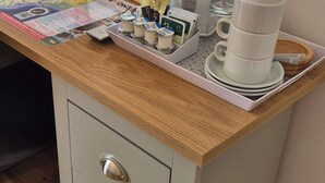 A wooden desk with a map, a kettle, and a stack of white cups. - Midway Guest House (Torquay)