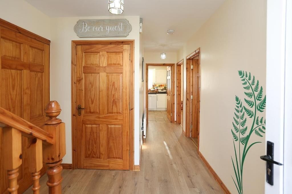 A hallway with wooden doors and a sign that reads 'Be our guest.'
