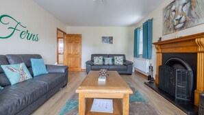 A living room with a sofa, a coffee table, a fireplace, and a painting on the wall. - The Ferns (Ballymoney)
