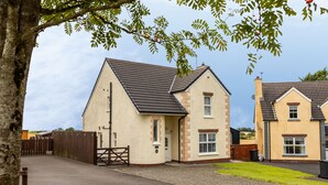 A residential area with two houses, a wooden fence, and a paved driveway. - The Ferns (Ballymoney)