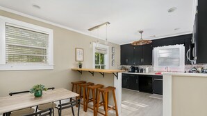 Una cocina moderna con una isla central, taburetes de bar y una mesa de comedor con sillas.