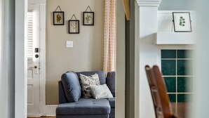Una sala de estar con un sofá gris, suelo de madera e impresiones botánicas enmarcadas en la pared.