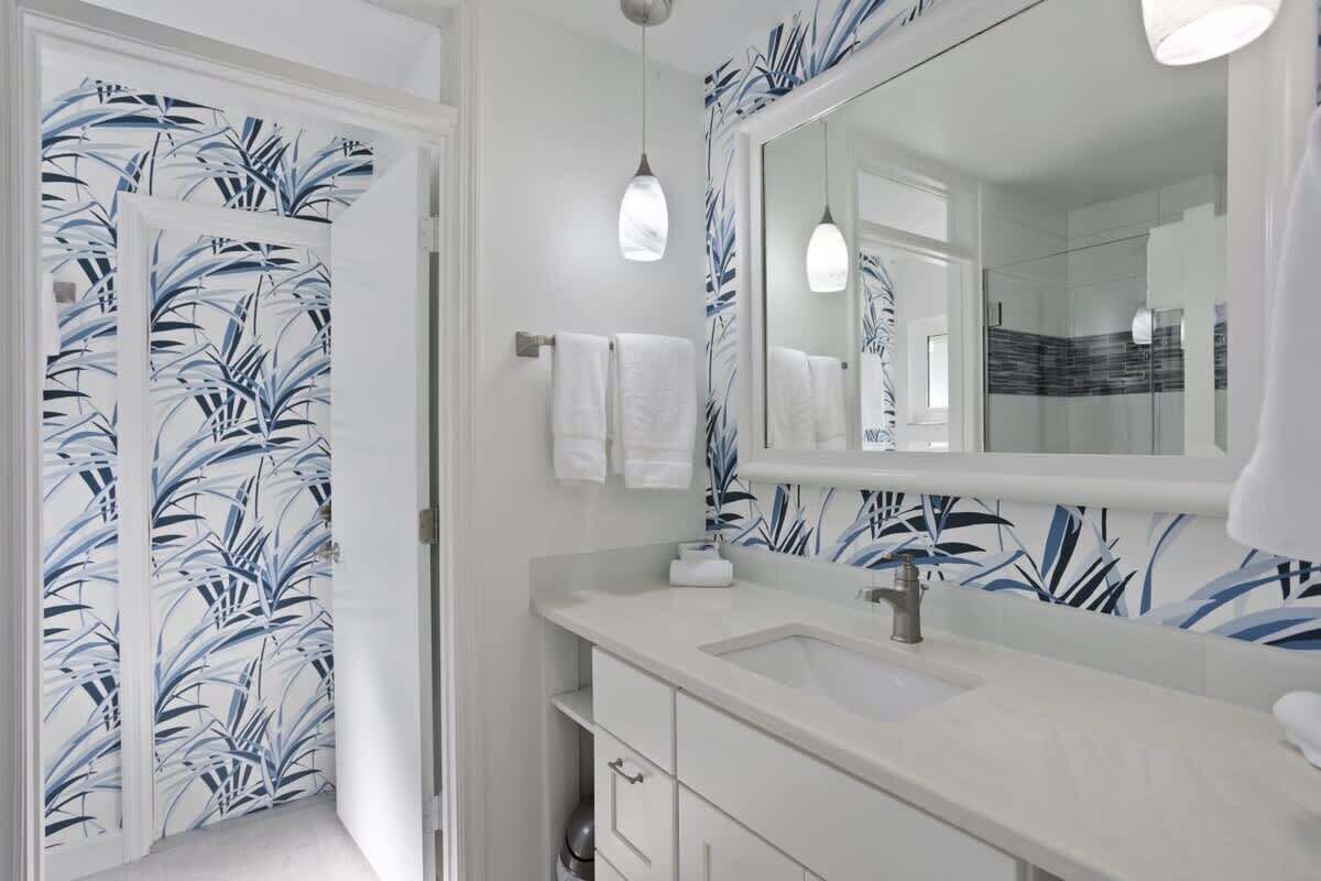 A bathroom with a white sink, a large mirror, and a shower area.