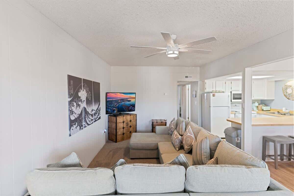A living room with a sofa, a television, and artwork on the wall.