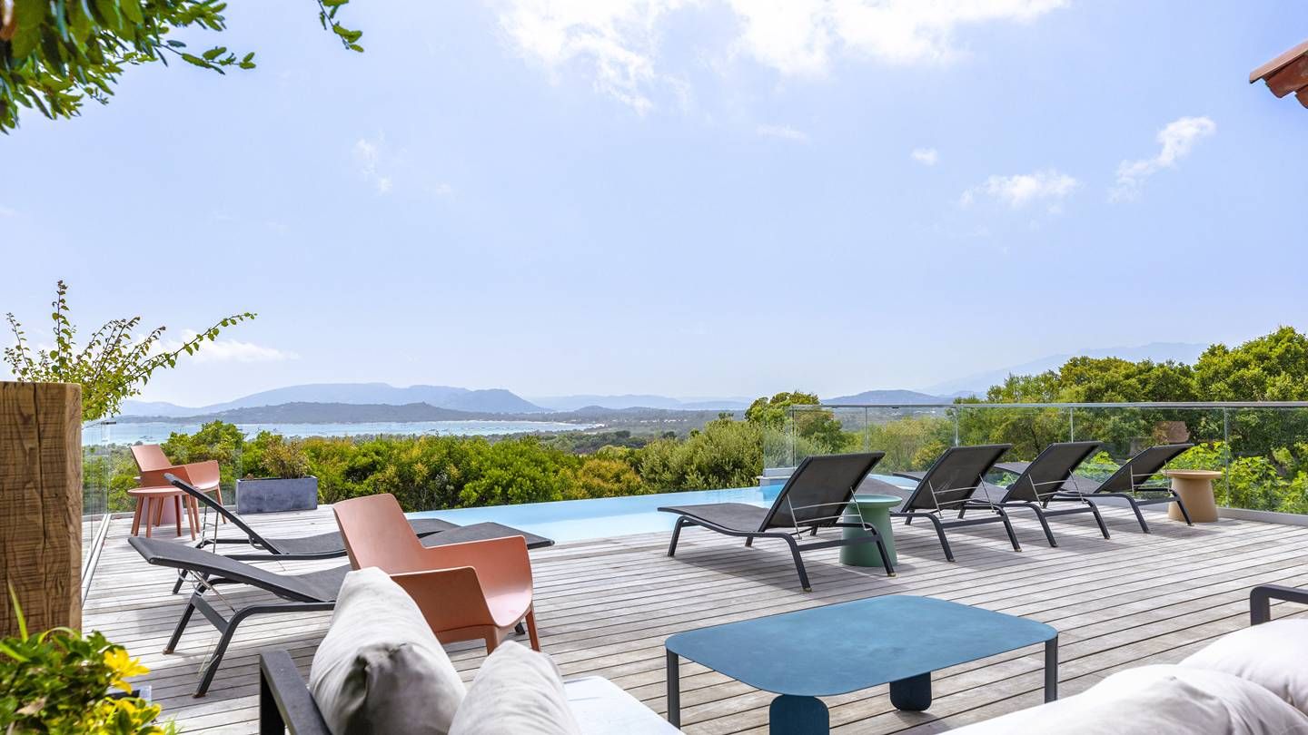Eine Terrasse mit Liegestühlen und einem Pool mit Blick auf eine malerische Landschaft.