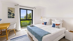 Une chambre à coucher avec un lit, un bureau et une fenêtre donnant sur un paysage verdoyant.