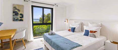 Un dormitorio con cama, escritorio y ventana con vista a zonas verdes.