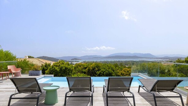 Un espace aménagé au bord de la piscine, avec des chaises longues et une vue sur le paysage.