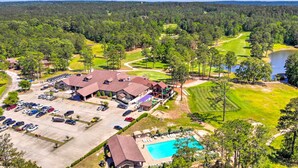 Un campo de golf con club house, aparcamiento y piscina.