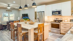 Una cocina moderna con armarios blancos, electrodomésticos de acero inoxidable y una isla central con sillas.