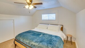 Un dormitorio con cama, ventilador de techo, ventana y puerta.