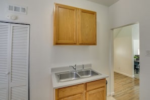 A kitchen with wooden cabinets, a double sink, and a white countertop. - 1 Block to Town! Convenient Logan Apartment (Logan)