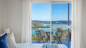 Une chambre avec une grande fenêtre donnant sur un paysage magnifique, avec un lac et des collines en toile de fond.
