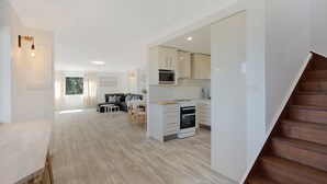 Une cuisine moderne avec des meubles blancs, un four à micro-ondes et une cuisinière. On y trouve également un coin repas avec une table et des chaises.