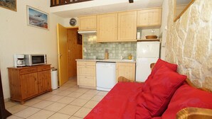 Eine kleine Küche mit Holzschränken, einer Mikrowelle, einem Geschirrspüler und einem Kühlschrank.