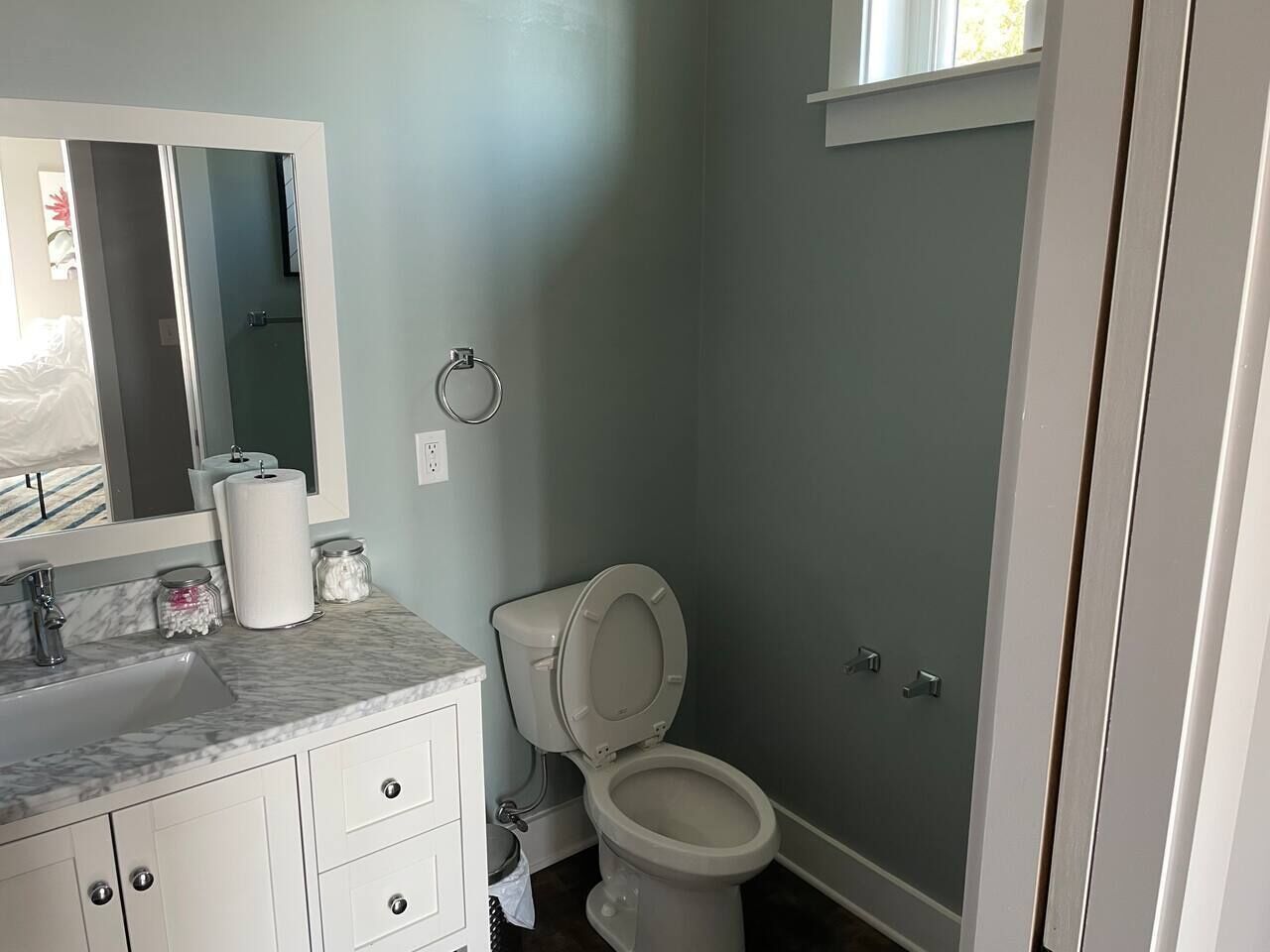 A bathroom with a toilet, sink, and mirror.