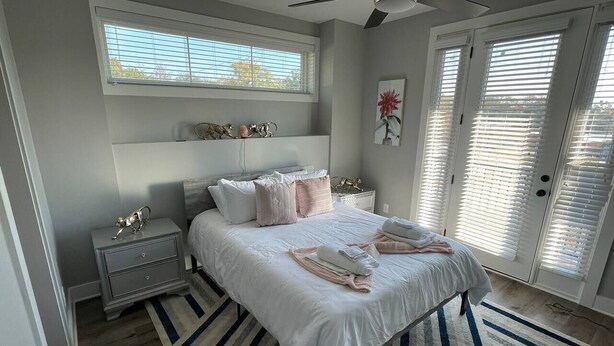 Una camera da letto con un letto, comodini, una finestra e una porta con persiane.
