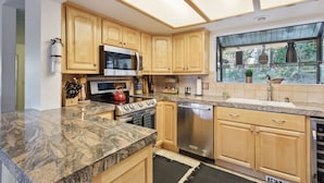 A modern kitchen with wooden cabinets, granite countertops, stainless steel appliances, and a large window offering a view of the outdoors. - "Modern" Zephyr, 3 mins to beach, 7 mins to Heavenly, Casinos (Zephyr Cove)