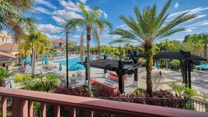 A resort pool area with lounge chairs, umbrellas, and palm trees.