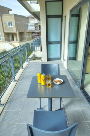 A balcony with a table, two chairs, a bowl of snacks, and two cans of drink. - Large & modern 3bedroom in prime location WPAC1-1 (St Julian's)
