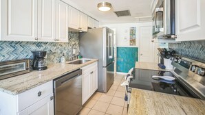Une cuisine moderne avec des meubles blancs, un réfrigérateur en acier inoxydable, un four à micro-ondes et une cuisinière.