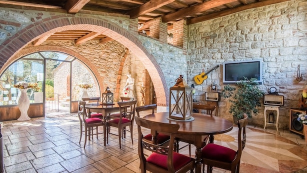 A rustic interior with stone walls, wooden furniture, and a TV mounted on the wall. - Apartment 'Agriturismo Ischieto - La Torretta' with Shared Pool, Wi-Fi and Air Conditioning (Rapolano Terme)