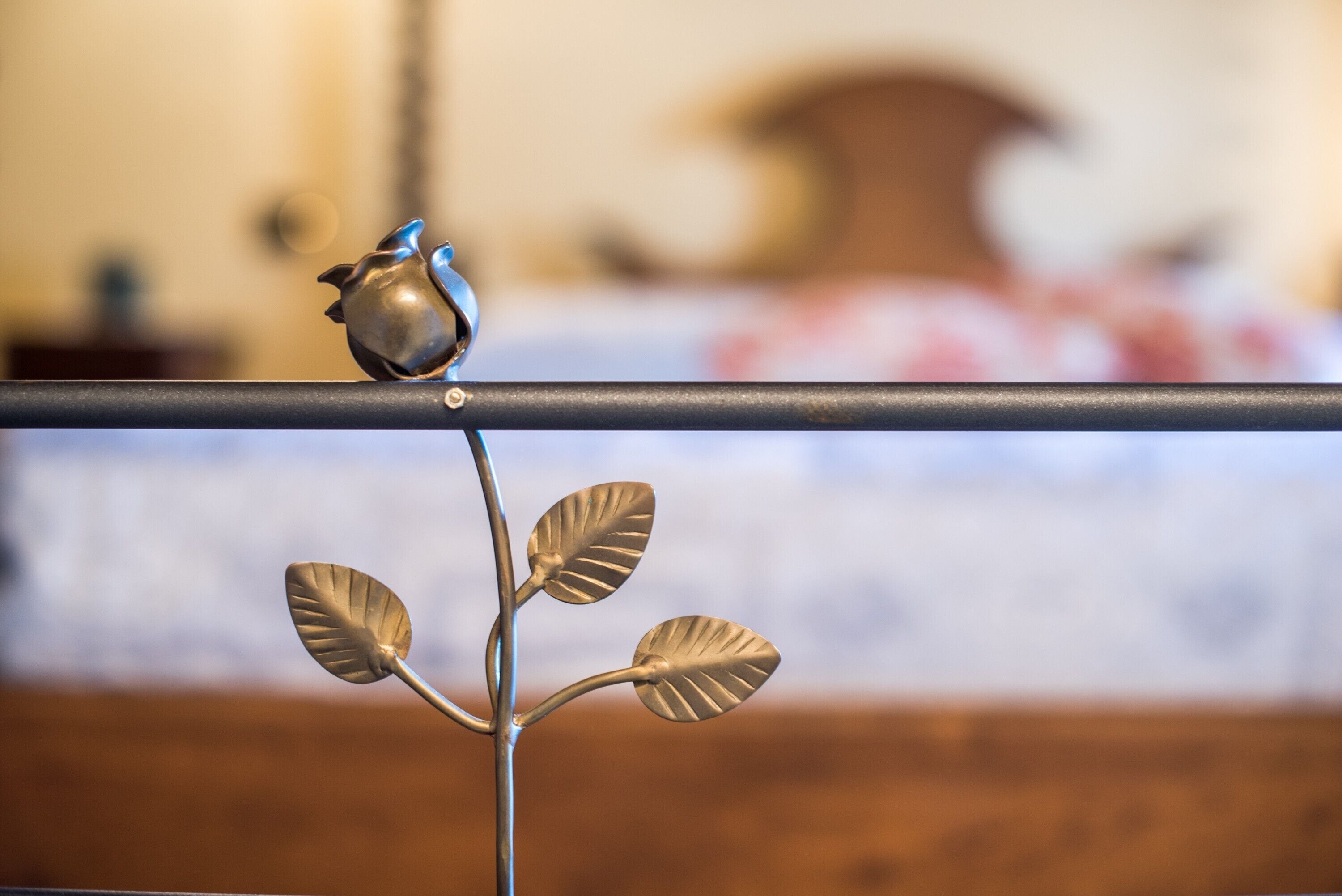 A metal sculpture with leaves and a bird on a horizontal bar.