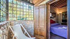 Ein Schlafzimmer mit einem Bett, einem Holzschrank, einem Fenster mit Blick auf Bäume und einem weißen Stuhl.
